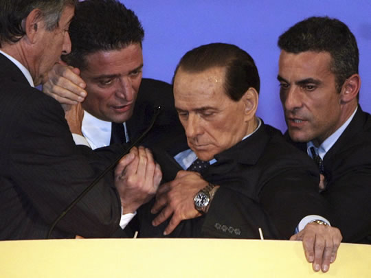 Silvio Berlusconi es ayudado por sus asistentes (Reuters)