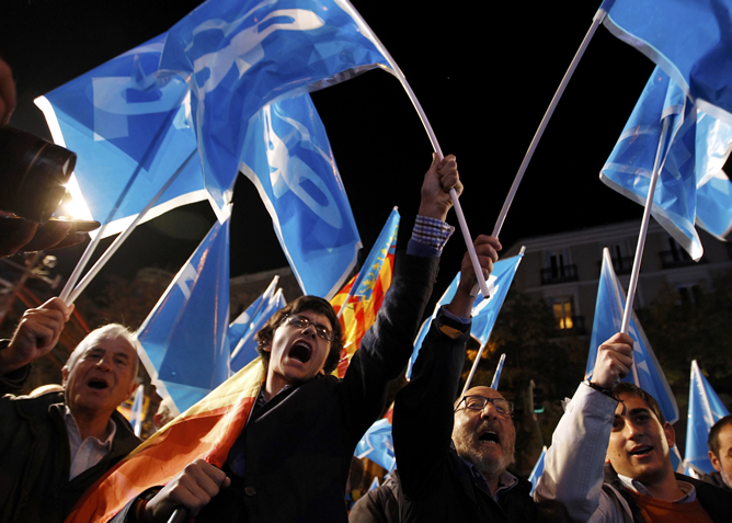 Varios simpatizantes del Partido Popular agitan sus banderas en la calle Génova