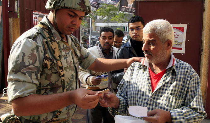 Un soldado egipcio comprueba la documentación de un hombre antes de votar en la primera ronda de las elecciones egipcias