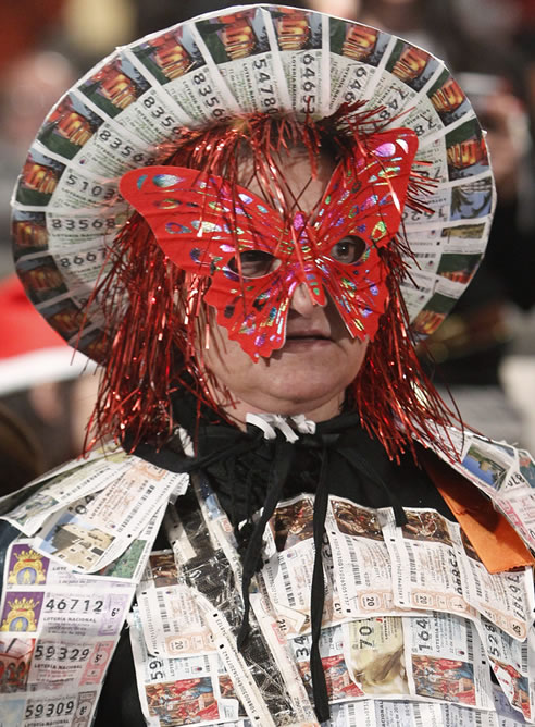 Una mujer disfrazada con numerosos décimos espera en el Palacio de Congresos de Madrid el comienzo del tradicional sorteo de la Lotería de Navidad, que se convierte en el mayor de la historia, con una dotación de cuatro millones de euros a la serie (400.000 euros al décimo).