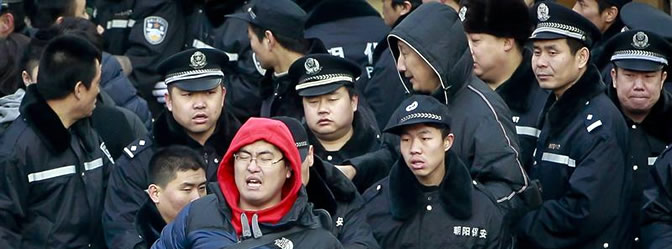 Policías chinos sacan a un hombre al intentar colarse en una fila en el exterior de una tienda Apple
