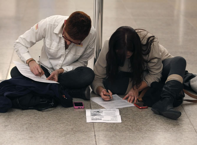 Dos pasajeros rellenan un formulario de reclamación en el aeropuerto de Barcelona