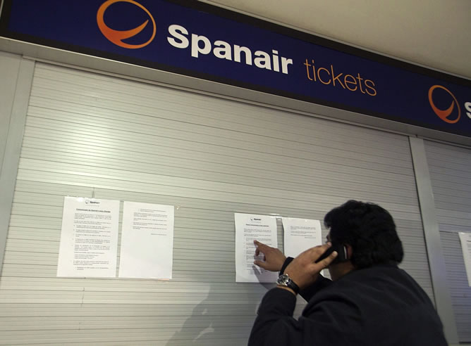 Un hombre lee el comunicado que Spanair tiene en su oficina del aeropuerto de Tenerife Norte Los Rodeos, en el que hace recomendaciones a los pasajeros tras su cese de operaciones aéreas