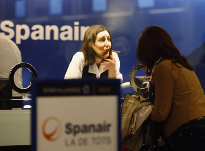 Una trabajadora de Spanair atiende a una afectada por la cancelación de su vuelo