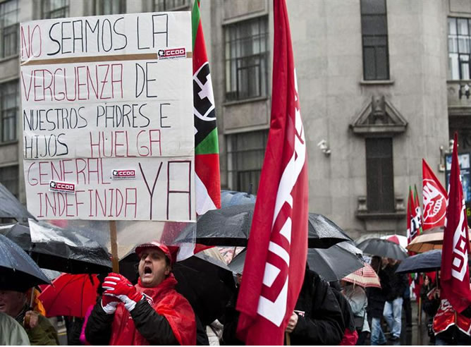 Un hombre porta un cartel llamando a la huelga general indefinida durante la manifestación en Bilbao. EFE