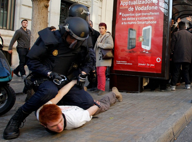 Un policía custodia a un detenido durante los incidentes entre estudiantes y policías registrados en el centro de Valencia