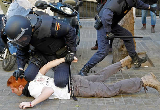 Un policía custodia a un detenido durante los incidentes entre estudiantes y policías registrados este lunes en el centro de Valencia