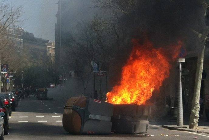Un contenedor arde en el cruce de las calles Enric Granados y París, en el centro de Barcelona