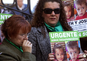 Dos mujeres portan carteles con fotografías de los niños onubenses Ruth y José Ortiz