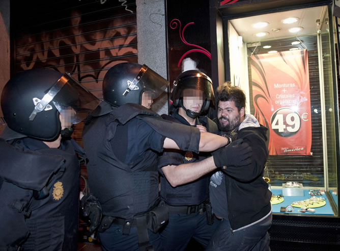 Varios policías jorcejean con un indignado durante el desalojo de la Puerta del Sol.