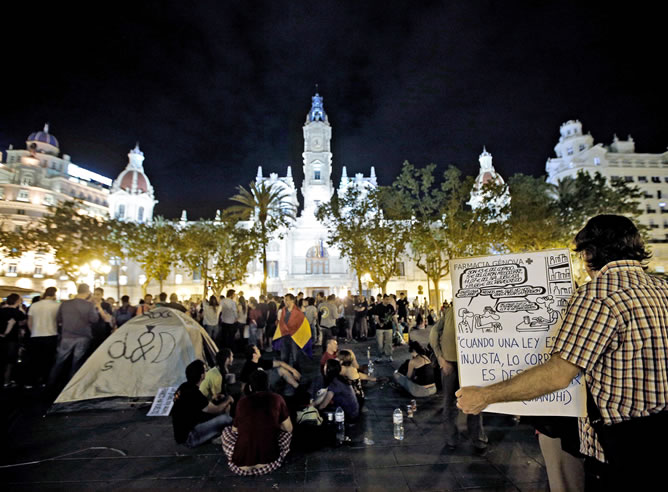 Unos 200 de manifestantes, que han participado en la marcha convocada por el colectivo 15M, permanecen en la plaza del Ayuntamiento de Valencia.