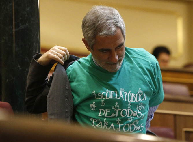 El diputado de IU, Gaspar Llamazares, se quita la chaqueta para dejar a la vista la camiseta verde con el lema 'Escuela pública de todos para todos' en apoyo de la jornada de huelga