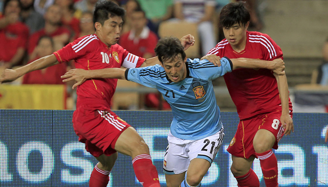 El centrocampista de la selección española, David Silva, intenta superar la defensa de los jugadores de China, Zheng Zhi y Hao Junmin, durante el partido que disputan esta noche en el estadio Olímpico de Sevilla, último partido preparatorio para la Eurocopa 2012