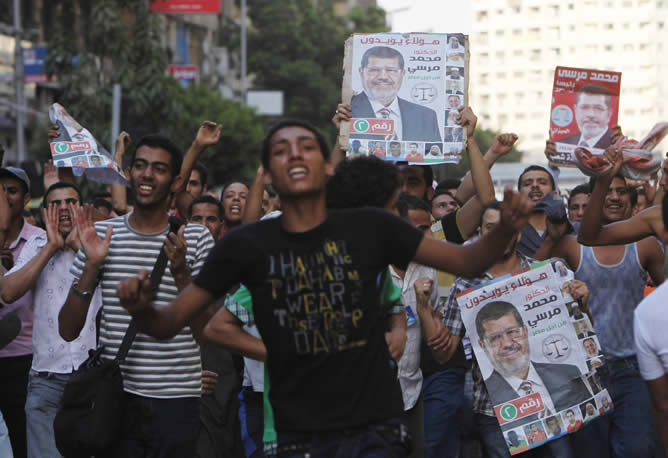 Seguidores del candidato de los Hermanos Musulmanes, Mohamed Mursi, celebran su victoria en las elecciones presidenciales en Egipto con carteles con su cara