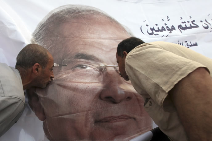 Dos hombres besan un poster de Ahmed Shafik