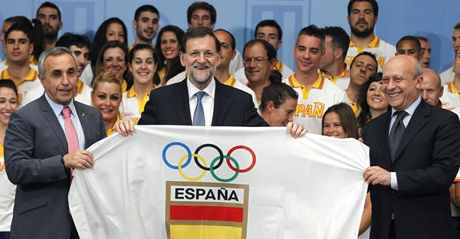 El presidente del Gobierno, Mariano Rajoy, junto al presidente del COE, Alejandro Blanco, y el ministro de Educación, Cultura y Deporte, José Ignacio Wert, muestran una bandera durante la recepción a los miembros del equipo español