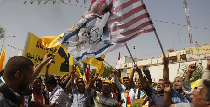 Varios manifestantes queman banderas israelíes y estadounidenses durante una protesta en Basra, la segunda ciudad de Irak