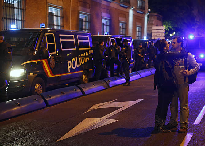 Una pareja, ante los furgones de los antidisturbios durante la protesta del miércoles en las proximidades del Congreso de los Diputados en Madrid