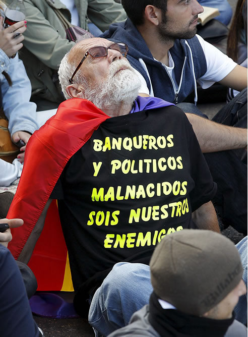Un hombre con una camiseta en la que protesta contra banqueros y políticos participa en la concentración en la plaza de Neptuno
