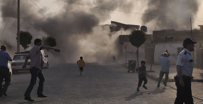 Unos ciudadanos turcos escapan del humo provocado por el estallido de una bomba de mortero lanzada desde Siria