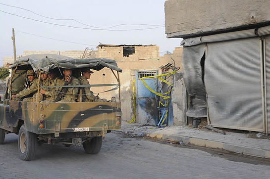 FOTOGALERIA: Soldados turcos pasan cerca de una casa afectada por un obús lanzado desde Siria