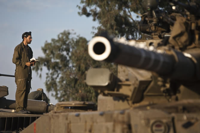 Un soldado israelí reza sobre un tanque cerca de la frontera con la Franja de Gaza.