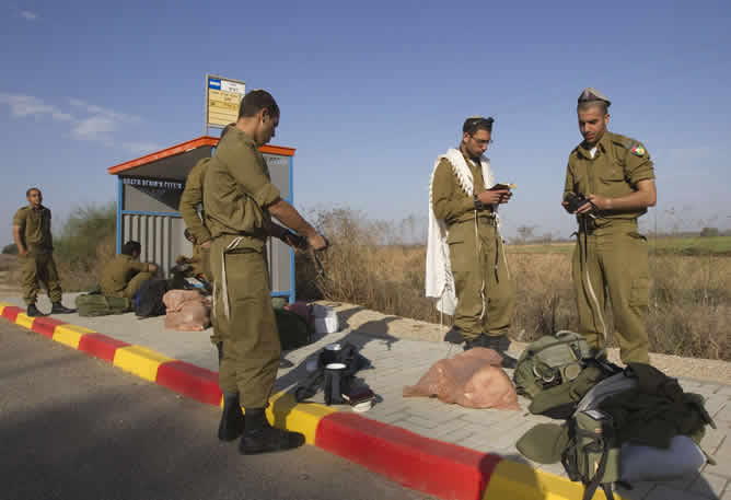 Un grupo de soldados de Israel esperar en una estación de autobuses cerca de la frontera en la Franja de Gaza, preparándose para una posible invasión terrestre.