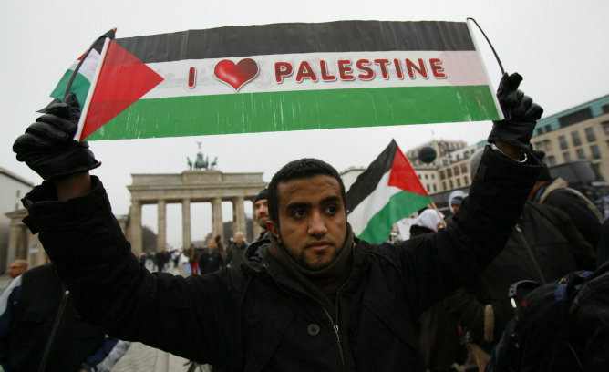 Un palestino sostiene una bandera palestina con el lema "Me encanta Palestina" durante una protesta de unos 100 palestinos fuera de Brandenburgo, en Berlín.