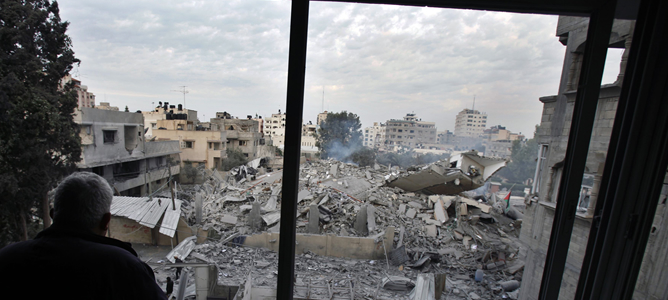 Un palestino mira desde su casa los daños provocados por el bombardeo israelí en la sede del Gobierno de Hamás en Gaza.