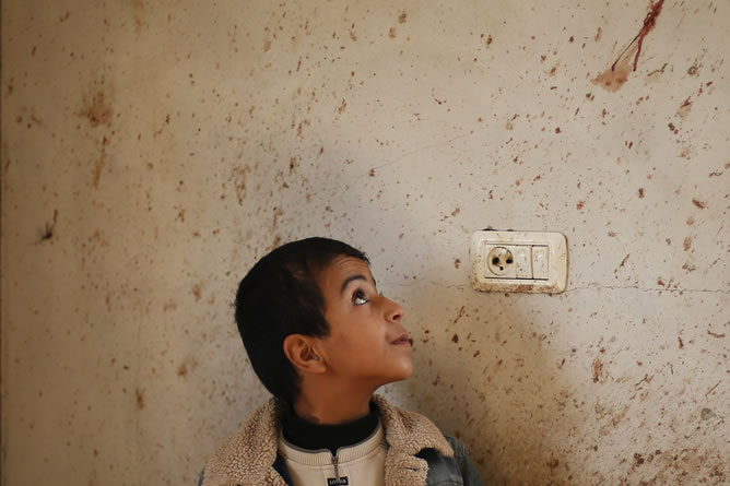 El hermano del chico palestino Basyoni Faris, que resultó muerto en un ataque aéreo israelí, mira su sangre en una pared de su casa. REUTERS/Suhaib Salem