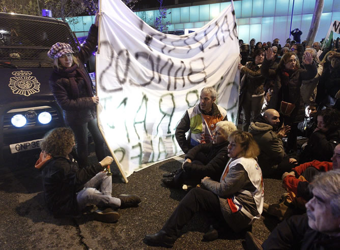 Varios manifestantes protagonizan una sentada durante la protesta organizada por la Mesa en Defensa de la Sanidad Pública contra las medidas sanitarias previstas por la Comunidad de Madrid para 2013, que ha tenido lugar esta tarde ante la Asamblea de Madrid.