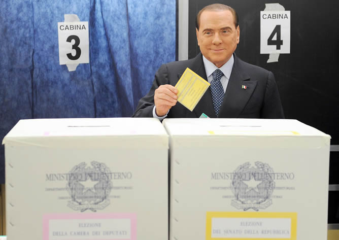 Silvio Berlusconi, sostiene su papeleta de voto para ser fotografiado antes de depositarlo en una urna de un colegio electoral de Milán.