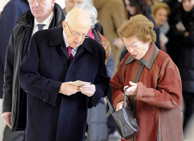 El presidente italiano Giorgio Napolitano, acompañado por su esposa Clio, comprueba su tarjeta de votación antes de emitir su voto en las elecciones generales italianas en un colegio electoral en Roma.