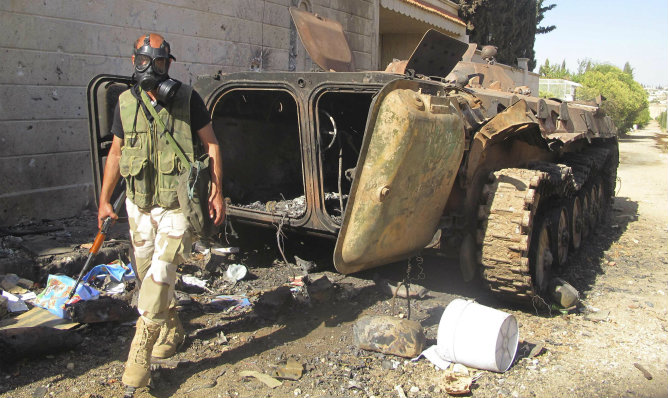 Un luchador del ejército libre sirio aparece con una máscara antigas después de la toma de un campo militar.