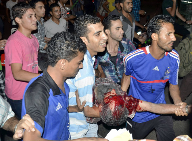 Los protestantes egipcios detractores del presidente Mohamed Mursi llevan a un hombre herido después de una explosión