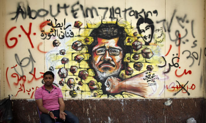 Un manifestante ante un 'graffiti' contra Mursi en el Palacio Presidencial de El Cairo
