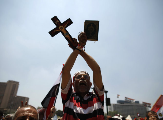 Un manifestante sostiene un ejemplar del Corán y una cruz durante una manifestación en la plaza de Tahrir