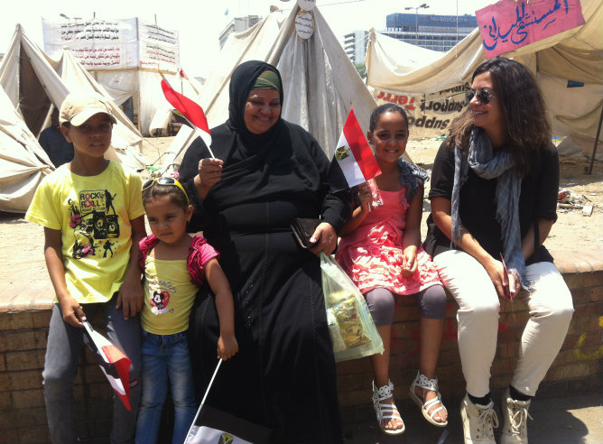 Una mujer y sus hijos ondean la bandera egipcia sonrientes junto a Àngels Barceló