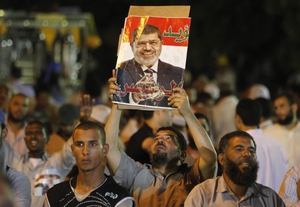 Un miembro de la Hermandad Musulmana y partidario del derrocado presidente egipcio, Mohamed Mursi sostiene un cartel del expresidente en El Cairo