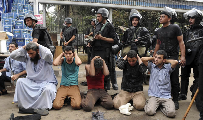 Varios miembros de las fuerzas de seguridad egipcias vigilan a un grupo de manifestantes arrestados durante el asalto a uno de los dos asentamientos de los simpatizantes del depuesto presidente Mohamed Mursi