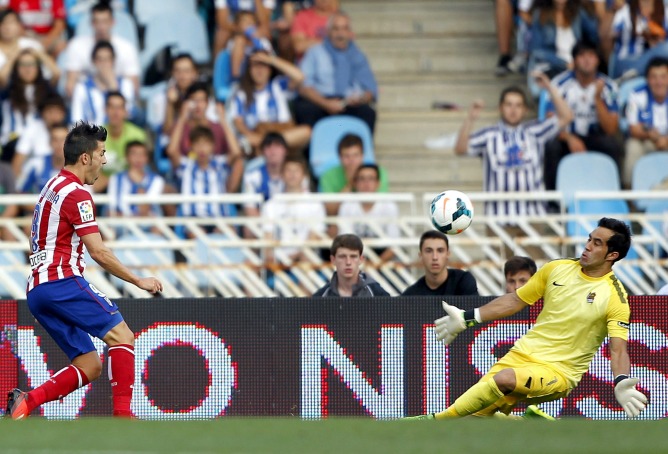 El delantero del Atlético de Madrid David Villa supera al portero de la Real Sociedad, el chileno Claudio Bravo.