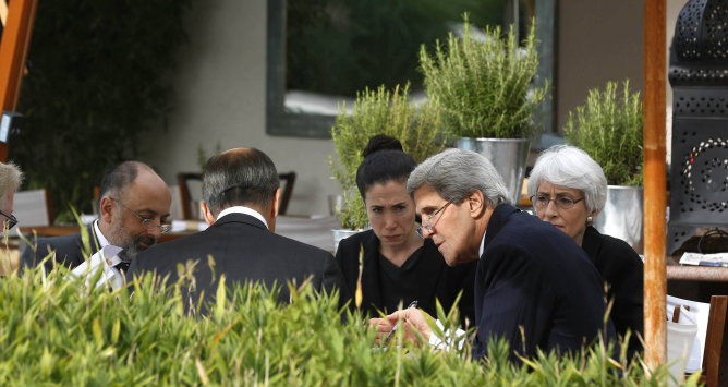 John Kerry junto a su secretaria y el ministro de Exteriores ruso, Sergei Lavrov (de espaldas), sentado al lado de sus principales colaboradores durante una reunión para negociar una solución al conflicto sirio