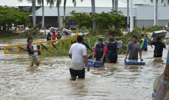 Varios vecinos de Acapulco se recuperan tras las inundaciones que ha dejado el huracán 'Ingrid' a su paso por México