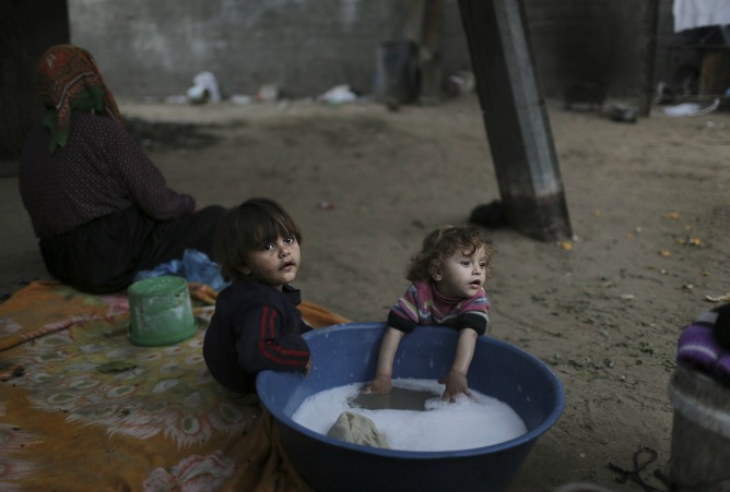 Dos niños se bañan en el campo de refugiados de Jabaliya durante un corte eléctrico sufrido en la Franja de Gaza