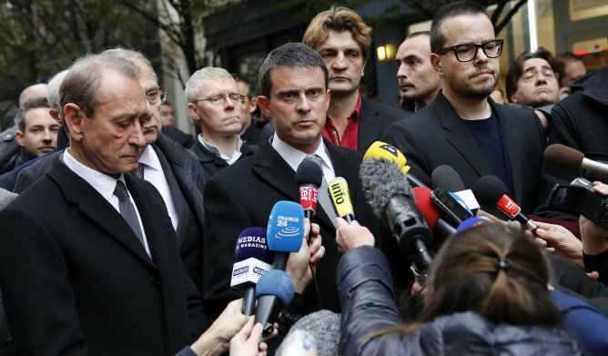 El ministro francés de Interior, Manuel Valls, acompañado por el alcalde de París, Bertrand Delanoe, y el periodista francés Nicolas Demorand, atienden a la prensa a las puertas de la sede del diario francés Libération