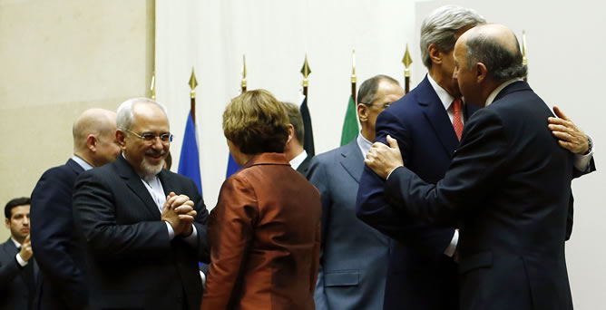 El ministro de exteriores iraní, Javad Zarif, habla con la alta representante de la UE, Catherine Ashton, mientras el secretario de Estado de EE UU, John Kerry se abraza con su homólogo francés, Laurent Fabius.