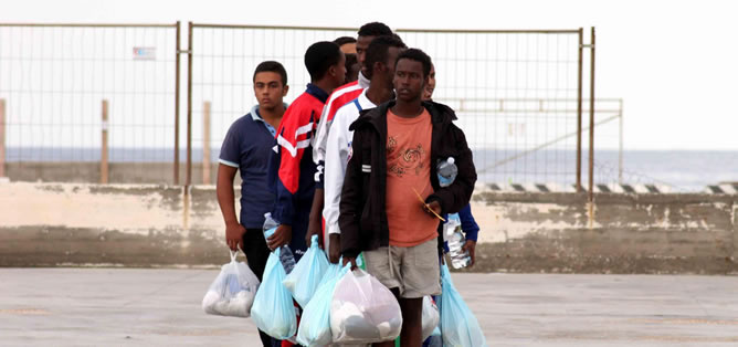 Un grupo de inmigrantes caminan por el puerto de Lampedusa