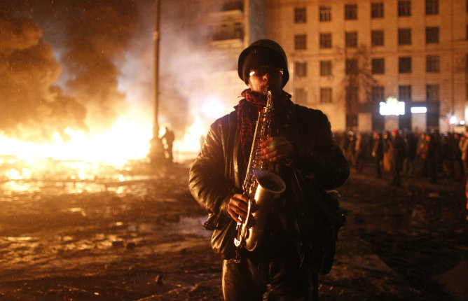 Un hombre toca el saxofón en medio de una zona en llamas en el centro de Kiev