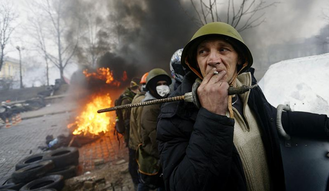 Un manifestante fuma un cigarrillo en las barricadas mientras continúan los enfrentamientos con los antidisturbios en la Plaza de la Independencia en Kiev