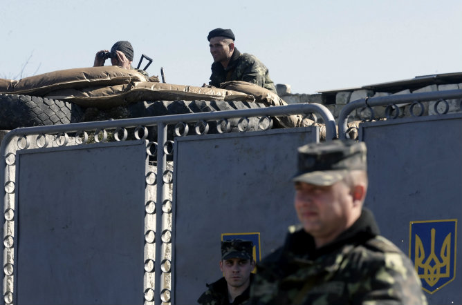 Dos soldados rusos observan a soldados armados sin identificar, presuntamente rusos (no aparecen), mientras hacen guardia en el territorio de una unidad militar ucraniana en la localidad de Bajchisarái (Ucrania)